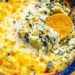 Creamy hot spinach artichoke dip served in a bowl with tortilla chips