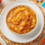 Homemade stovetop applesauce in a bowl with apples and cinnamon